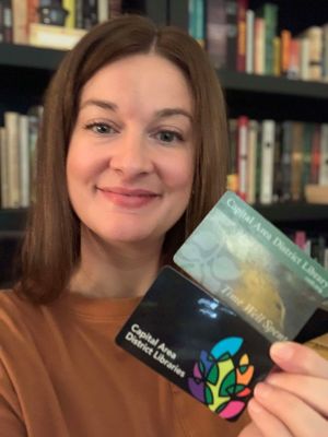 a woman smiles while holding an old and new CADL card