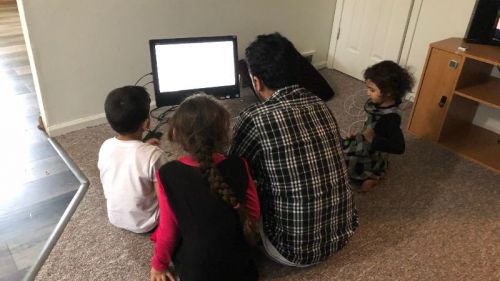 Refugee family uses computer donated by library. 