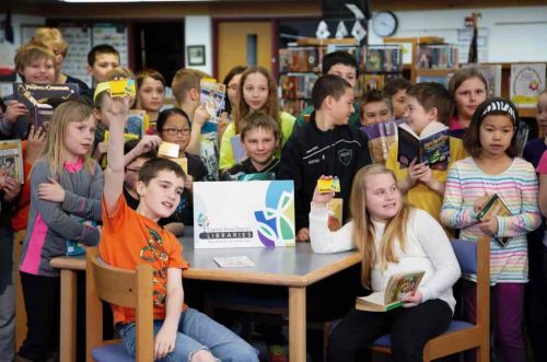 Kids holding up library cards. 